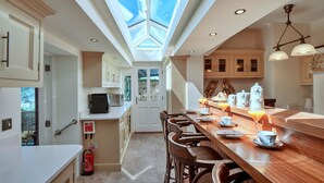 A modern kitchen with a skylight, wooden bar, and white cabinetry. - Penley Villa (Kingsand)