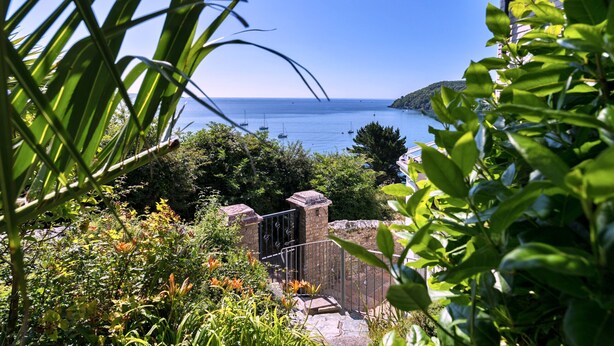 A coastal view with a clear sky, a stone gate, and lush greenery. - Penley Villa (Kingsand)