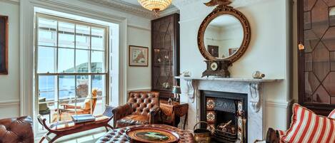 A traditional living room with leather furniture, a fireplace, and a large mirror.