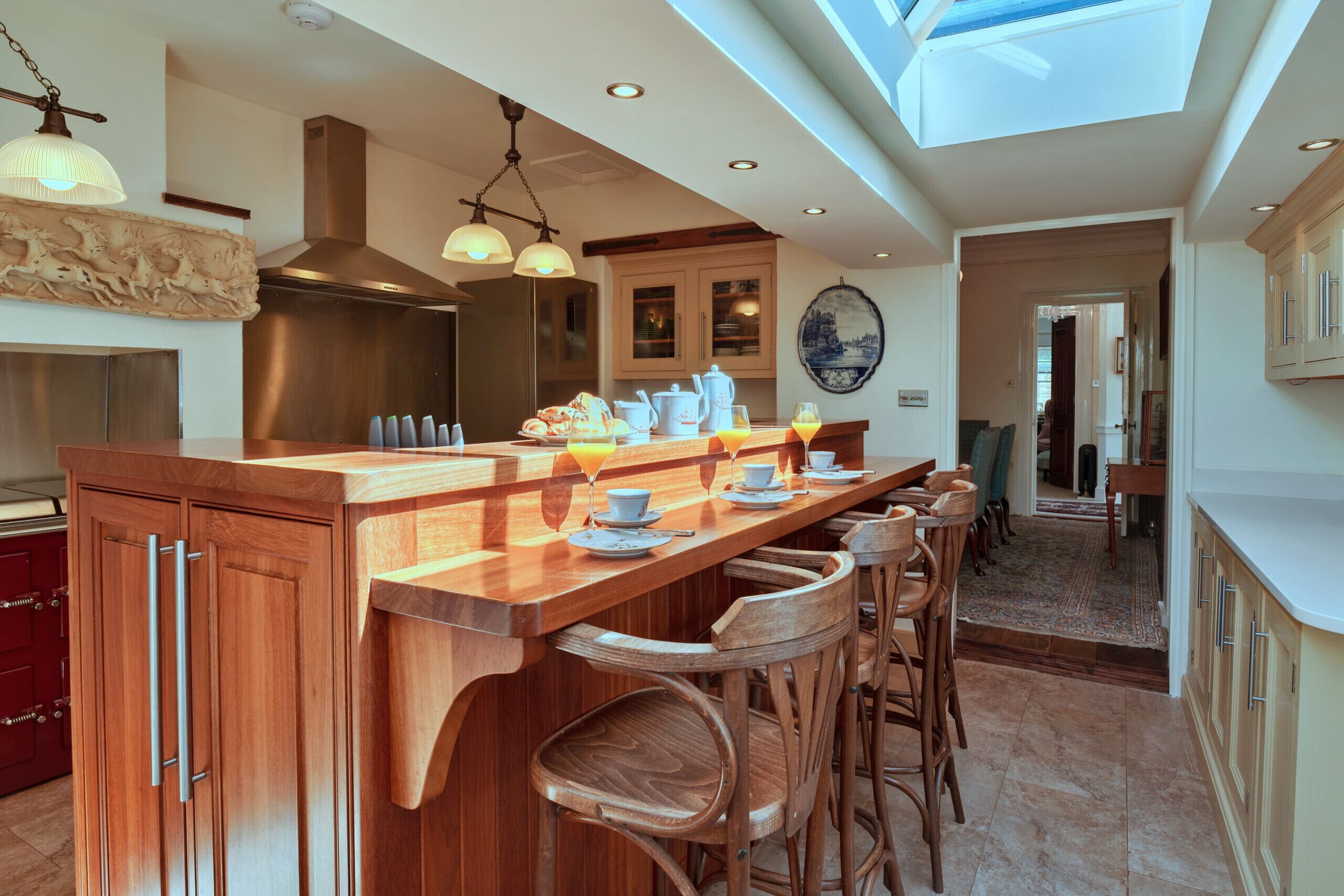 A modern kitchen with a central island, wooden bar stools, and a skylight above.