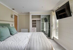 A bedroom with a bed, a wardrobe, and a television.