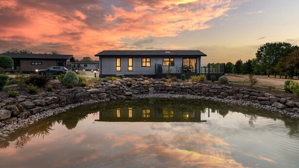 Une maison moderne avec un mur en pierre et un bassin devant.