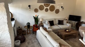 Una sala de estar con un conjunto de sofá, una mesa de centro, un televisor y adornos en la pared.