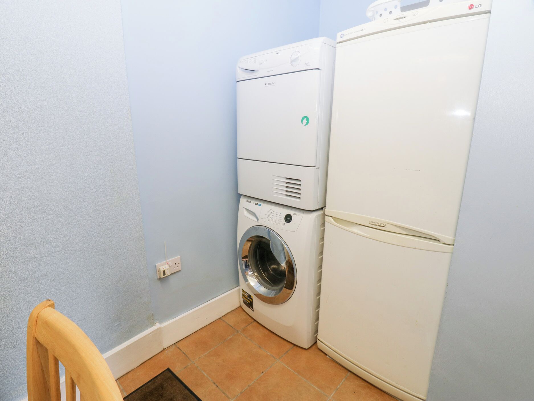 Zona de lavandería con lavadora, secadora y electrodomésticos apilados.
