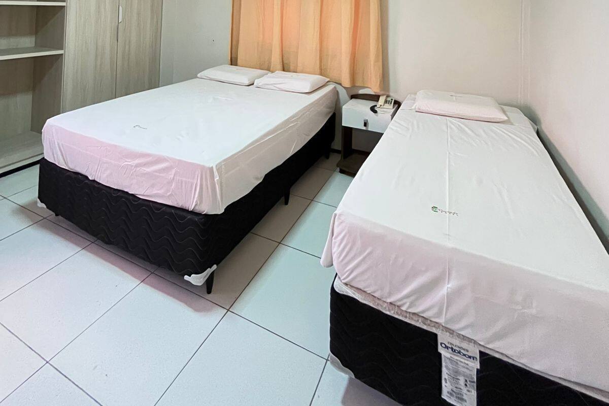 A room with two beds, a wardrobe, and an air conditioning unit.