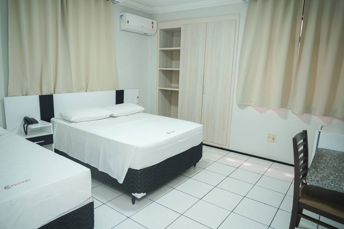 A hotel room with a bed, bedside table, chair, and a wardrobe.