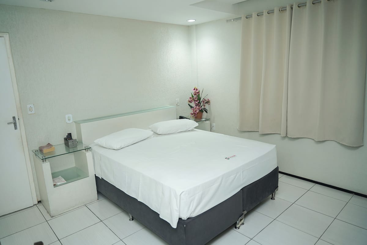 A neatly arranged bedroom with a bed, bedside table, and a small potted plant.