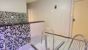 A small, modern kitchen with a ceiling fan, a tiled backsplash, and a dining area with a table and chairs. - Hotel Visconde  (Sobral)