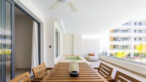 Ein modernes Zimmer mit Holztisch, Deckenventilator und Blick auf Pool und Gebäude.
