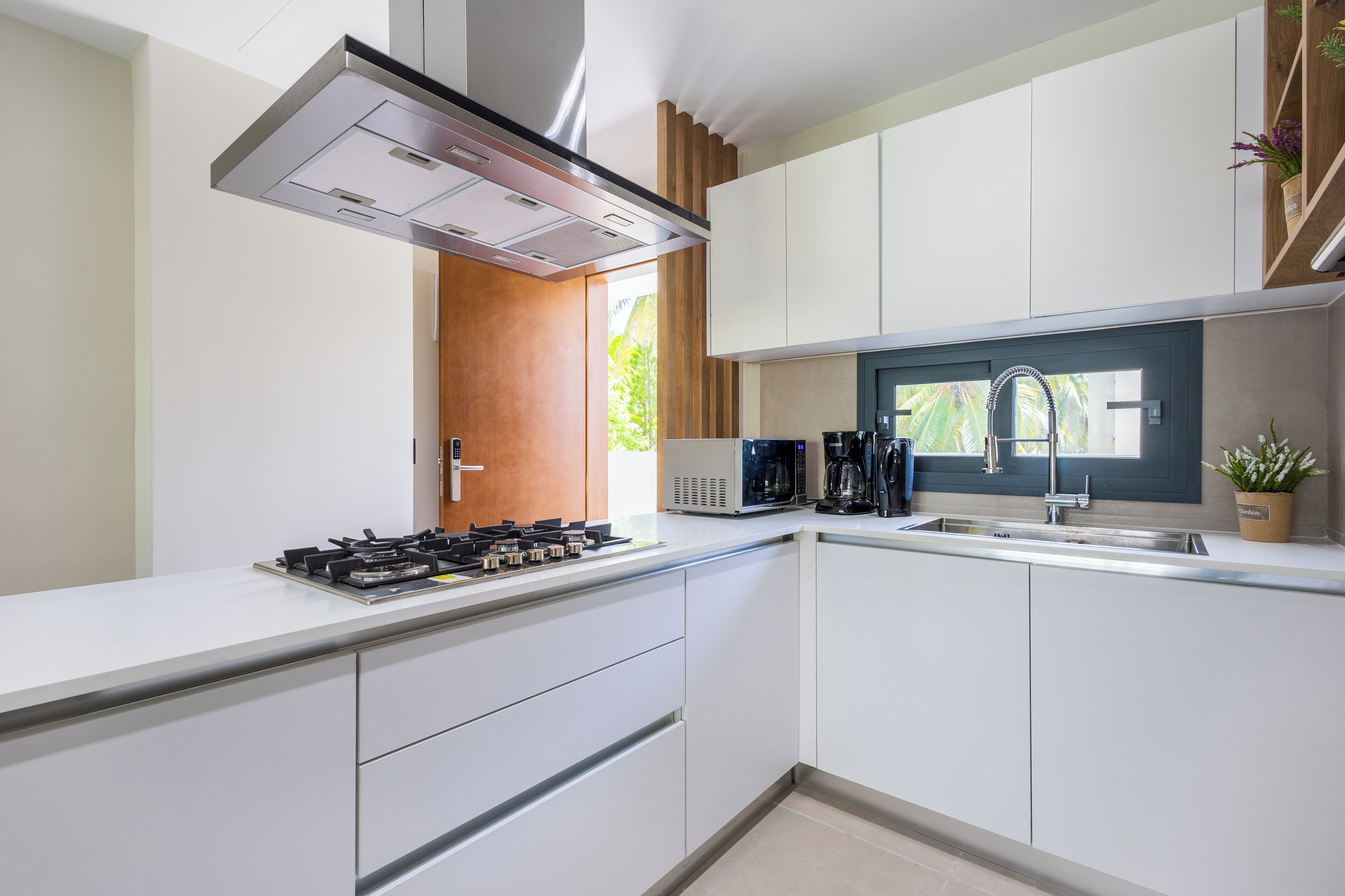 A modern kitchen with white cabinetry, a gas stove, a microwave, and a coffee maker.