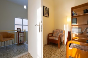 A room with a wooden bookshelf, a framed picture on the wall, a chair, and a door leading to another room.