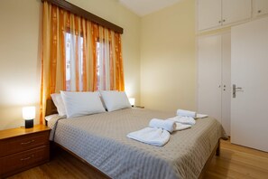 A neatly made bed with white linens, a bedside lamp, and a wooden nightstand. - Valira Stathmos Home - Rustic Charm Cottage W Garden (Messini)