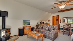 A cozy living room with a fireplace, a television, a sofa, and a dining area.