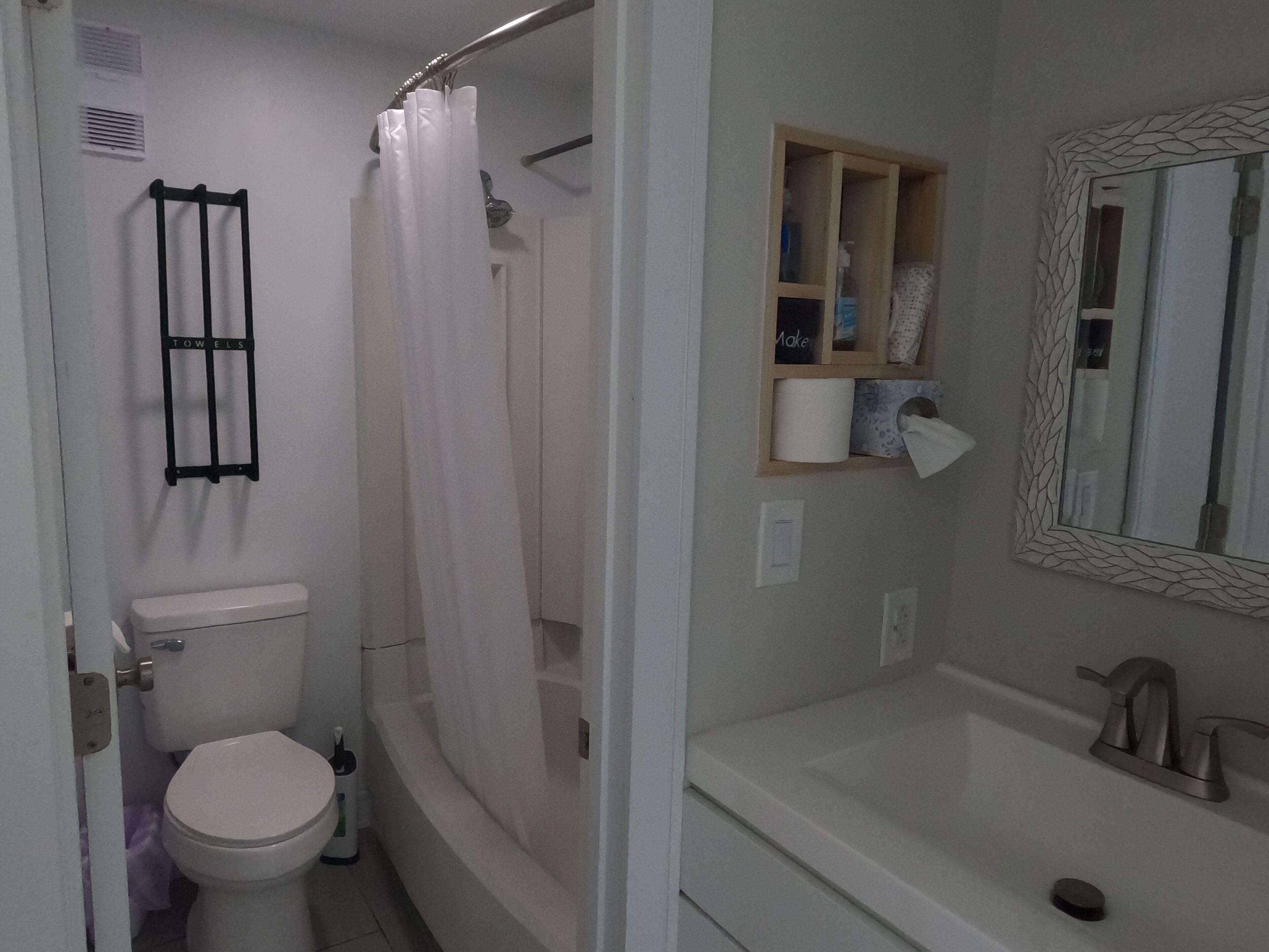 A bathroom with a toilet, shower curtain, and a sink with a mirror.