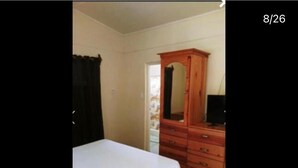 Ein Schlafzimmer mit einem Bett, einem Holzschrank und einem Spiegel.