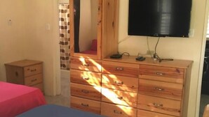 Ein Schlafzimmer mit einem Bett, einem Schminktisch, einem Fernseher und einem kleinen Tisch.