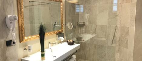 Un baño moderno con un espejo grande, un secador de pelo, un lavamanos y una zona de ducha.