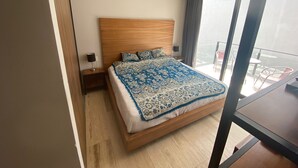 A modern hotel room with a large bed, wooden headboard, and a balcony with outdoor seating. - Magnificent location, Rooftop with Ocean View (Playa del Carmen)