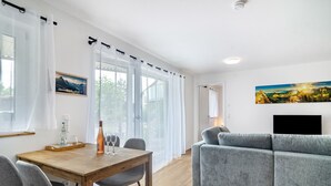 Una sala moderna con un sofá, una mesa de comedor con sillas y un televisor.