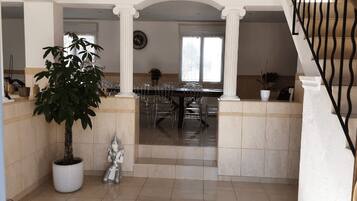 Un'ampia sala da pranzo con soffitto alto, colonne e una scalinata.