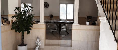 Un comedor espacioso con techo alto, columnas y una escalera.