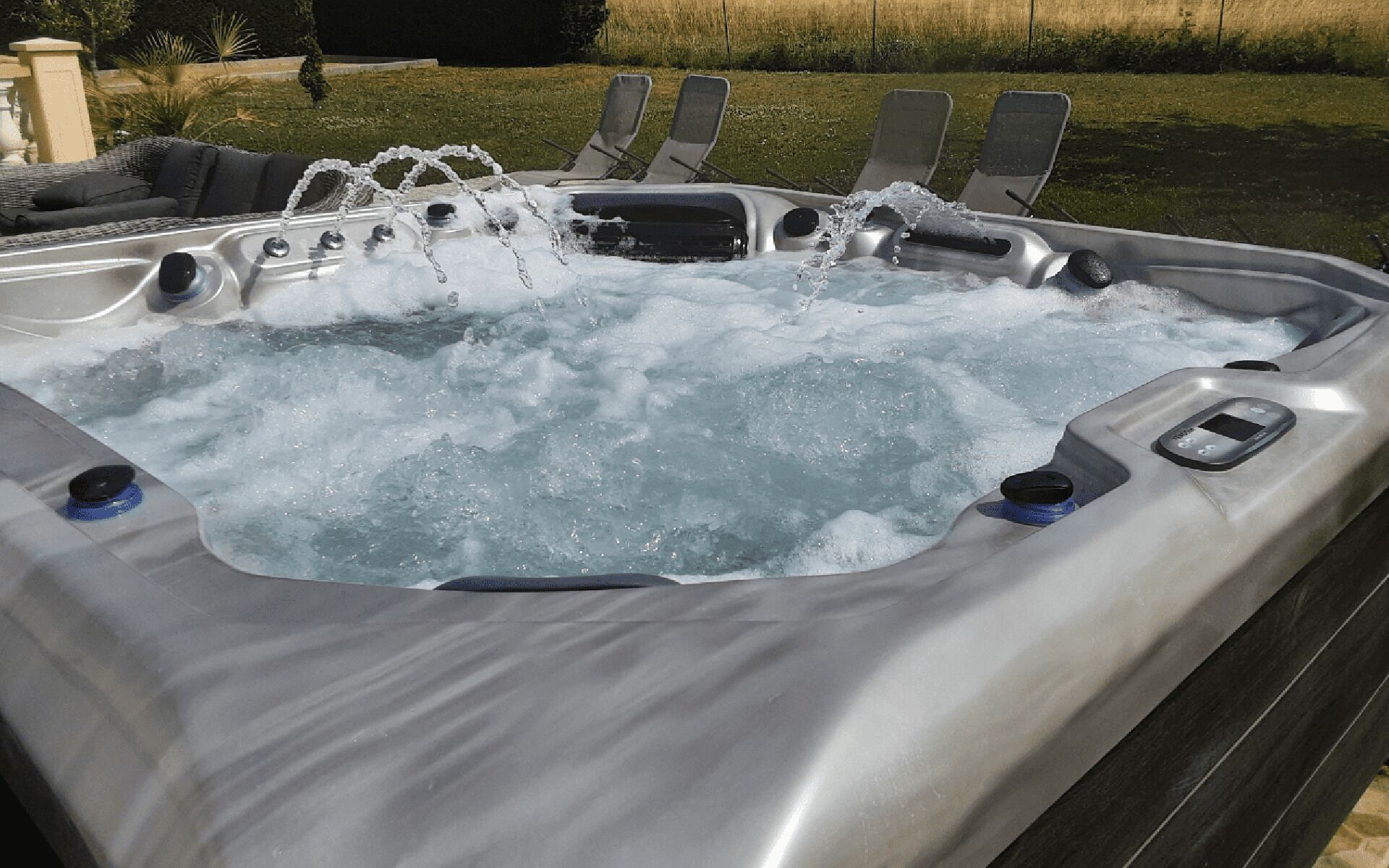 A hot tub with multiple jets, a control panel, and a seating area with lounge chairs.