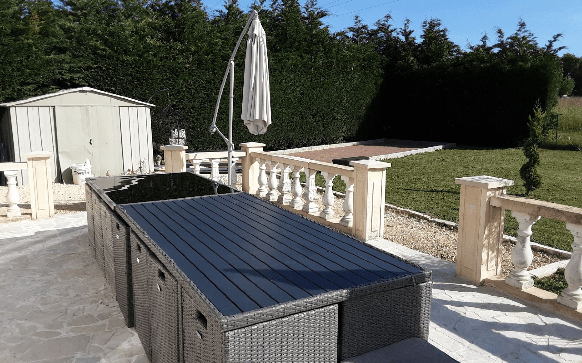 A covered outdoor seating area with a pergola, a small shed, and a well-maintained lawn.