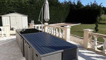 A covered outdoor seating area with a pergola, a small shed, and a well-maintained lawn.