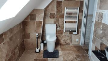 Un baño con inodoro, toallero y zona de ducha.