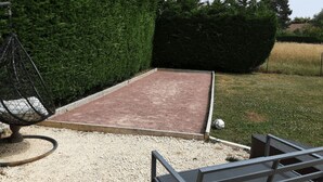 En have med en belagt terrasse, en hængestol og en metalbænk.