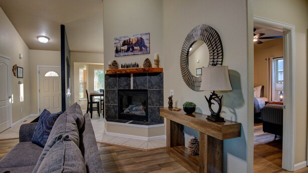 A living room with a fireplace, a sofa, and a console table with a mirror. - Modern Mountain Home w/ Hot Tub, Fenced Yard & Near Lakes (Pagosa Springs)