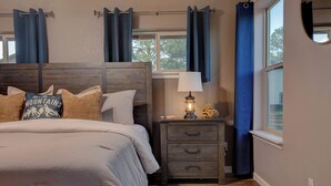 A bedroom with a bed, nightstand, lamp, and curtains. - Modern Mountain Home w/ Hot Tub, Fenced Yard & Near Lakes (Pagosa Springs)