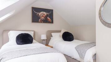 Ein Schlafzimmer mit zwei Betten, einer Deckenleuchte, einem wandmontierten Spiegel und einem Gemälde eines Stiers.