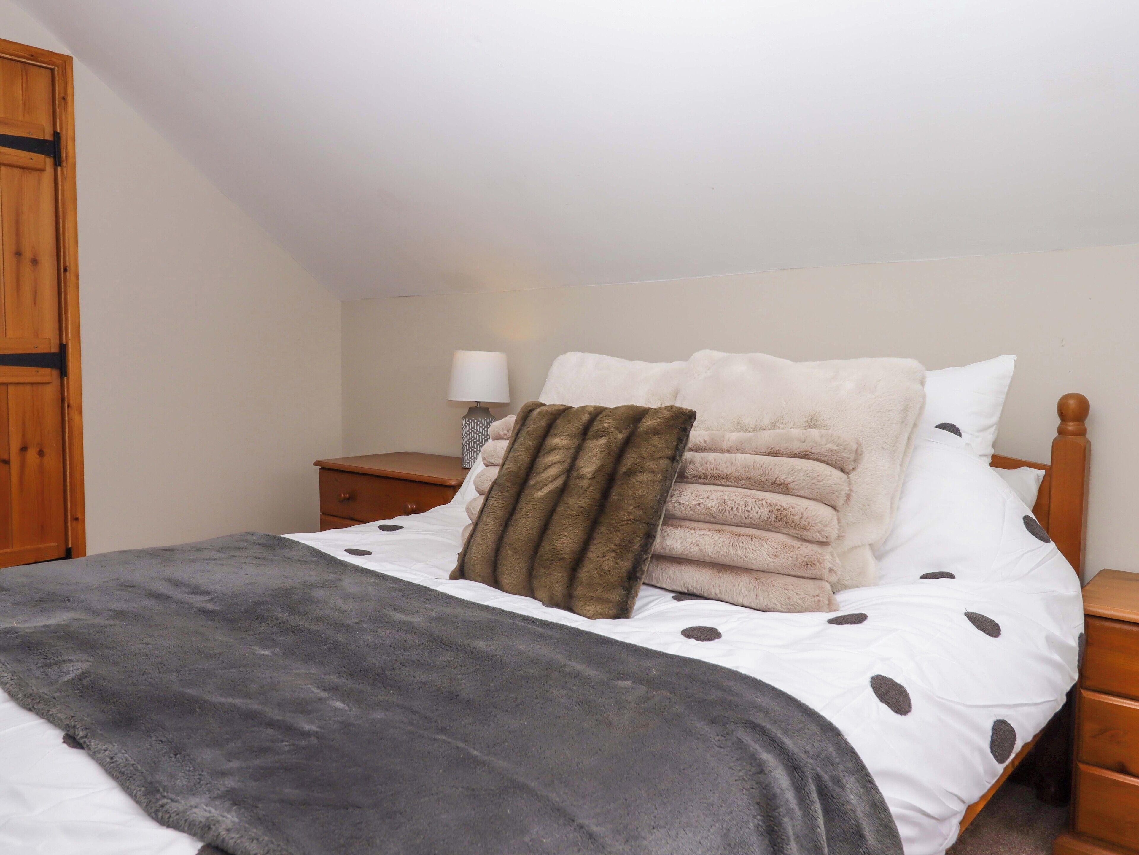 A bedroom with a bed, a nightstand, a lamp, and a wooden wardrobe.