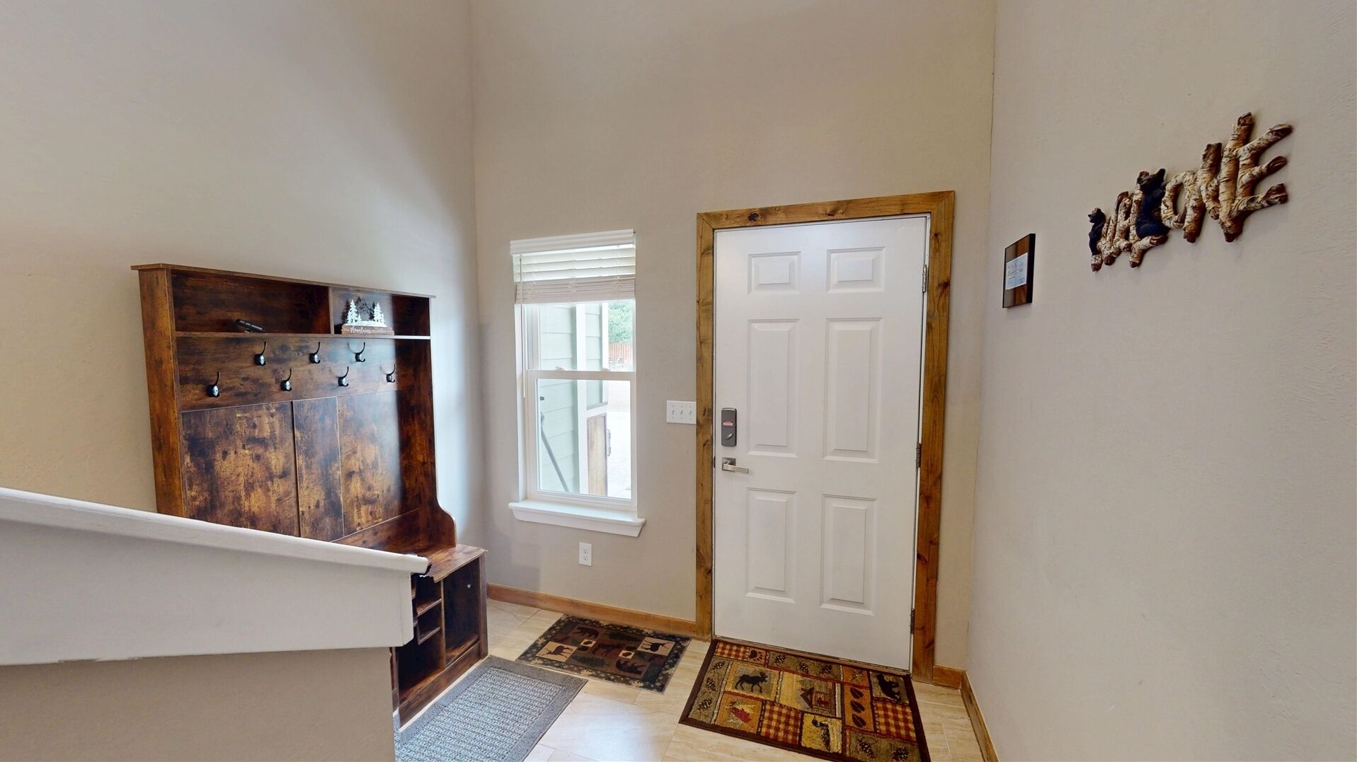 A staircase with a wooden handrail, a white door with a wooden frame, and a wall-mounted sign.
