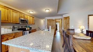 Une cuisine spacieuse dotée de plans de travail en granit, d’armoires en bois et d’un îlot central.