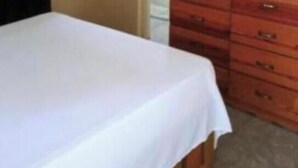 Un dormitorio con una cama, un aparador de madera y un espejo.
