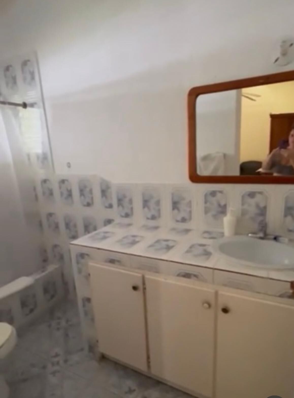 A bathroom with a toilet, sink, and mirror.