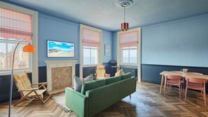 A room with a green sofa, wooden floor, a fireplace, and a dining table with chairs. - Host Stay 18 The Zetland (Saltburn-by-the-Sea)