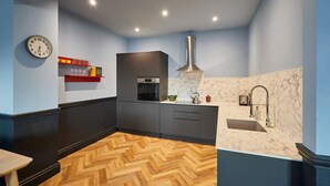 A modern kitchen with a herringbone wooden floor, a built-in oven, a stainless steel range hood, and a marble backsplash. - Host Stay 18 The Zetland (Saltburn-by-the-Sea)