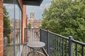 Ein Balkon mit Tisch und Stühlen mit Blick auf eine Straße und ein historisches Gebäude.