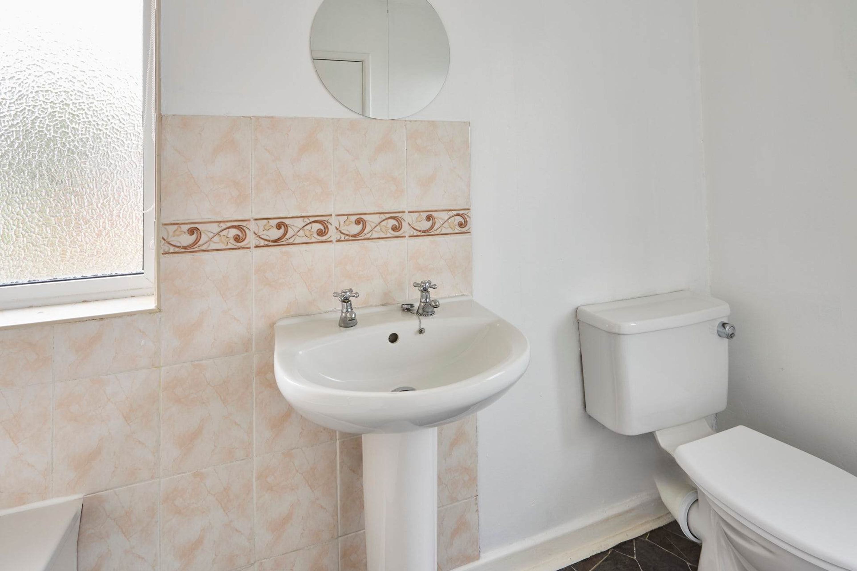 A bathroom with a white sink, a toilet, and a mirror on the wall.