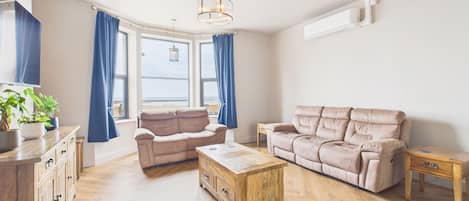A modern living room with a beige sofa, a wooden coffee table, and a wooden side table.