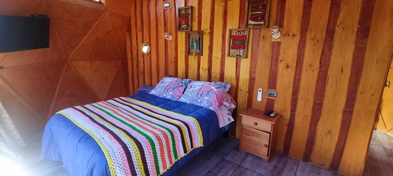 Una habitación con paneles de madera, una cama, una mesita de noche y adornos en las paredes.