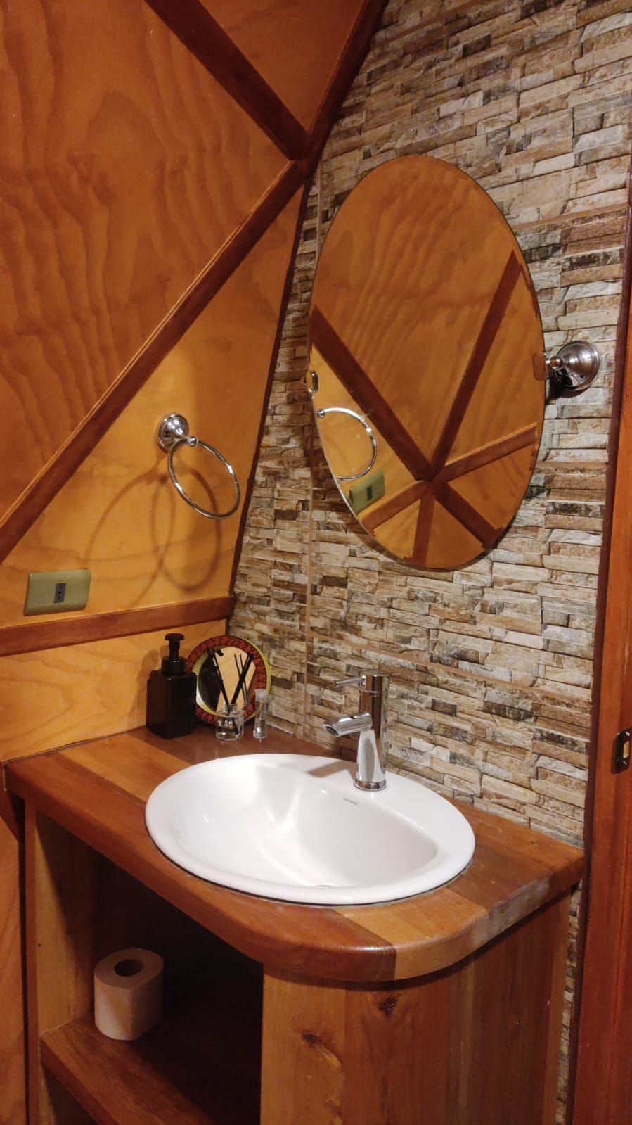 A wooden vanity with a white sink, a mirror, and a towel ring.