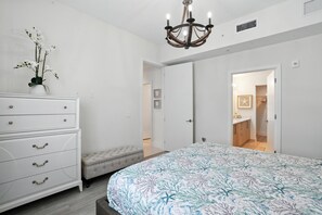 Une chambre à coucher avec un lit, une commode, un banc et un lustre.
