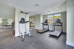 Een sportschool met loopbanden, een gewichtbank en een spiegel.