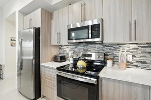 Una cocina moderna con electrodomésticos de acero inoxidable, armarios de madera y salpicadero de azulejos.