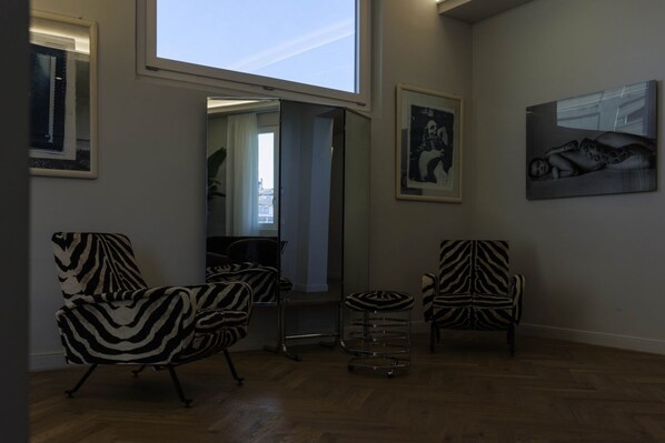 A spacious room with a large window, zebra-striped chairs, a small round table, and two framed artworks on the walls.
