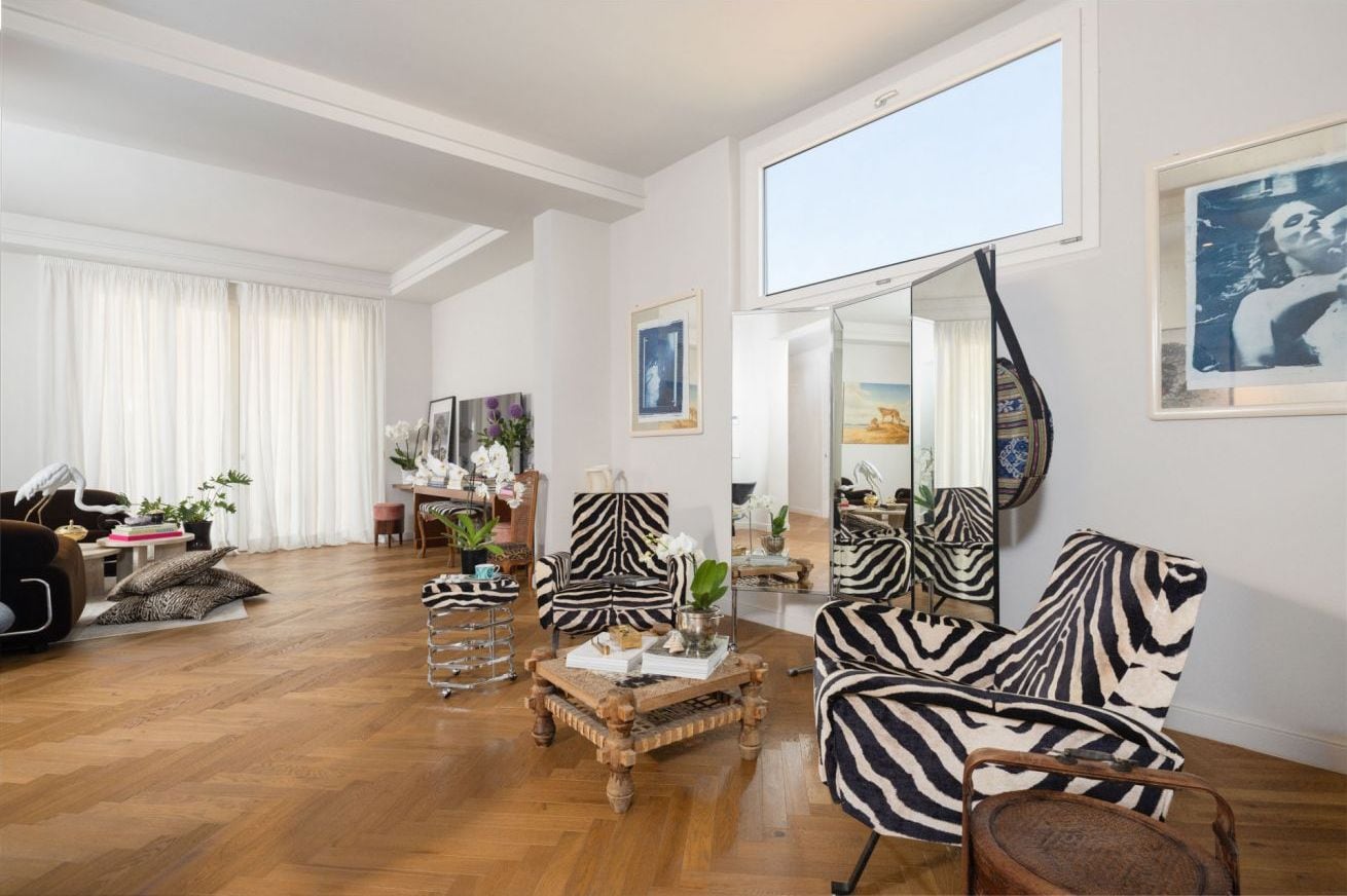 A spacious living room with a large mirror, zebra-striped chairs, and a wooden coffee table.